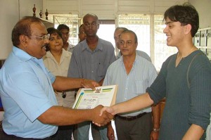 Foto: Best geslaagde Jatesh Mahespalsingh van het VWO neemt uit handen van waarnemend directeur Niermalkoemar Badloe van de VHK-scholengemeenschap zijn diploma in ontvangst.-