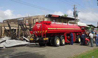 De brandweer blust de brand aan twee zakenpanden in Nieuw-Nickerie af.   