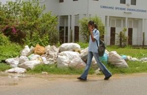 DWT foto / Beta Debidien:Een scholier loopt voorbij het vuil dat langs de weg is blijven liggen door de actie van de vuilophaaldienst in het district Nickerie.-.