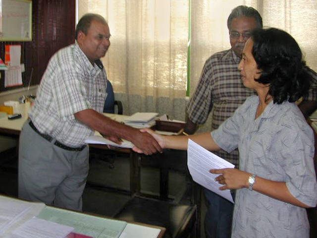 Ramini Amathardji Slamet 26 jaar in dienst bij OW ontvangt uit handen van sectiehoofd Haricharan Chotoe haar beschikking.